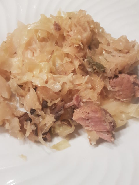 Ein Teller Sauerkraut mit Fleischstücken auf einem weißen Teller, warme und heimelige Stimmung